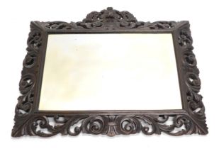 A rectangular wall mirror, with bevelled plate, the oak frame carved with scrolls around a central l