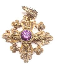 A Middle Eastern white metal pendant, of filigree design set with central purple paste stone, white