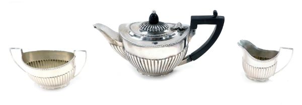 A late Victorian silver tea set, of oval semi fluted design, comprising teapot (AF), milk jug and su