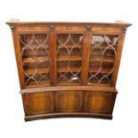 A mahogany convex shaped bookcase, the moulded dentil cornice above three glazed doors enclosing she