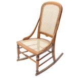 A late Victorian beech rocking chair, with a caned back and seat.