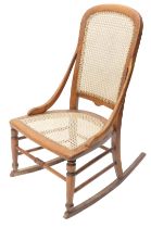 A late Victorian beech rocking chair, with a caned back and seat.