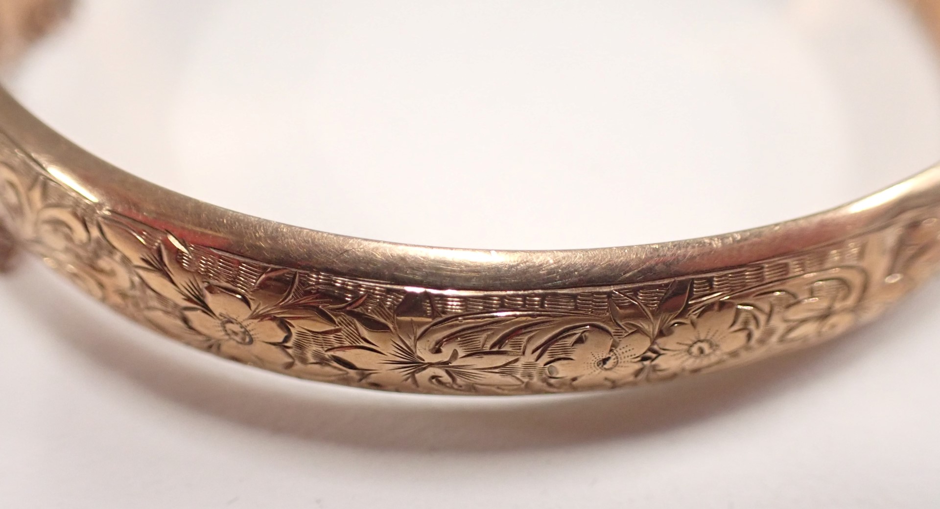 A George V 9ct rose gold hinged bangle, of half hoop design, with floral scroll decoration and safet - Image 2 of 4