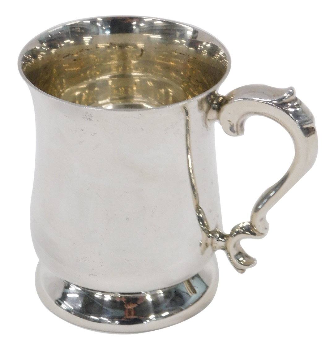 An Elizabeth II silver mug, of plain campana shaped design, with query handle, on tapered foot, 10cm