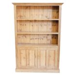 A pine dresser, the top with a moulded cornice above two shelves, the base with two panelled doors,