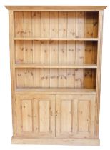 A pine dresser, the top with a moulded cornice above two shelves, the base with two panelled doors,