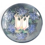 A Moorcroft pottery pin tray, decorated with a design of flowers and leaves, on a mottled blue groun