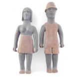 A pair of African carved tribal figures, modelled in the form of a gentleman and lady, the man weari