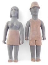 A pair of African carved tribal figures, modelled in the form of a gentleman and lady, the man weari