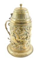 A 19thC continental embossed brass lidded tankard, decorated with figures boar hunting, and a scroll