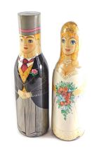 A pair of Russian painted bottle holders, each in the form of a bride and groom, 39cm and 36cm high.