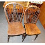 A pair of wheelback dining chairs.
