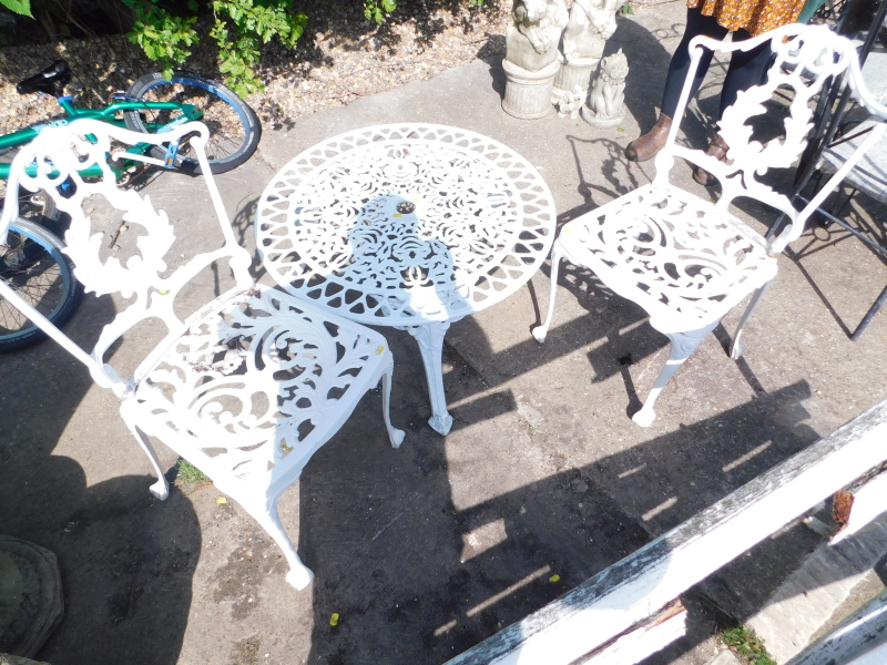 A painted cast iron garden set, comprising table and two chairs.