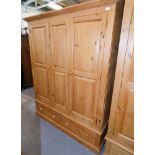 A modern pine triple wardrobe, moulded cornice above three doors and two drawers, on plinth base, 19