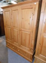 A modern pine triple wardrobe, moulded cornice above three doors and two drawers, on plinth base, 19