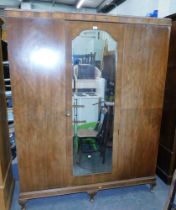 A walnut triple wardrobe, with central mirrored door, on cabriole legs.