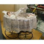 A wrought metal doll's pram, with linen throws and doll.