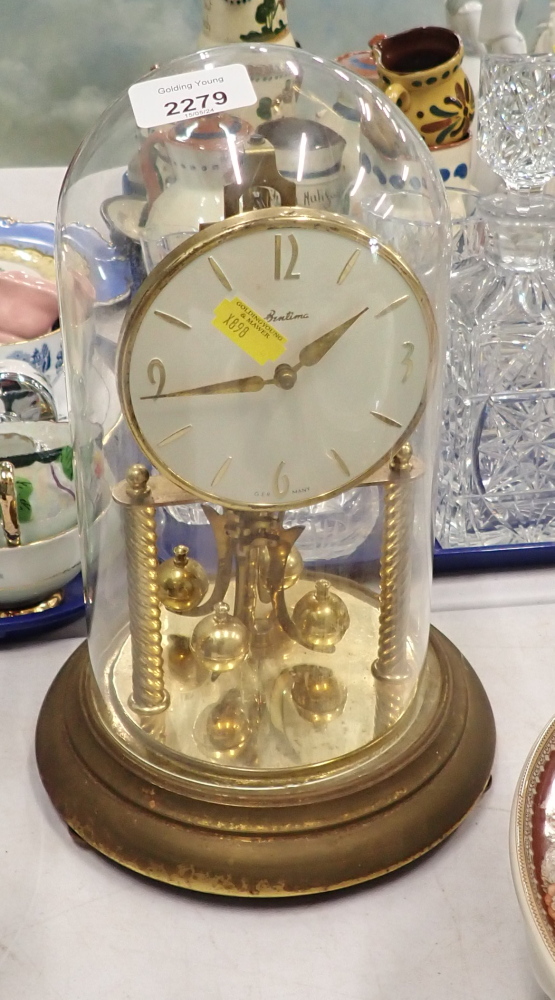 A brass anniversary clock, with glass dome.