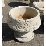 A reconstituted stone fleur de lys pattern urn, stylised with three petal design, on a circular foot