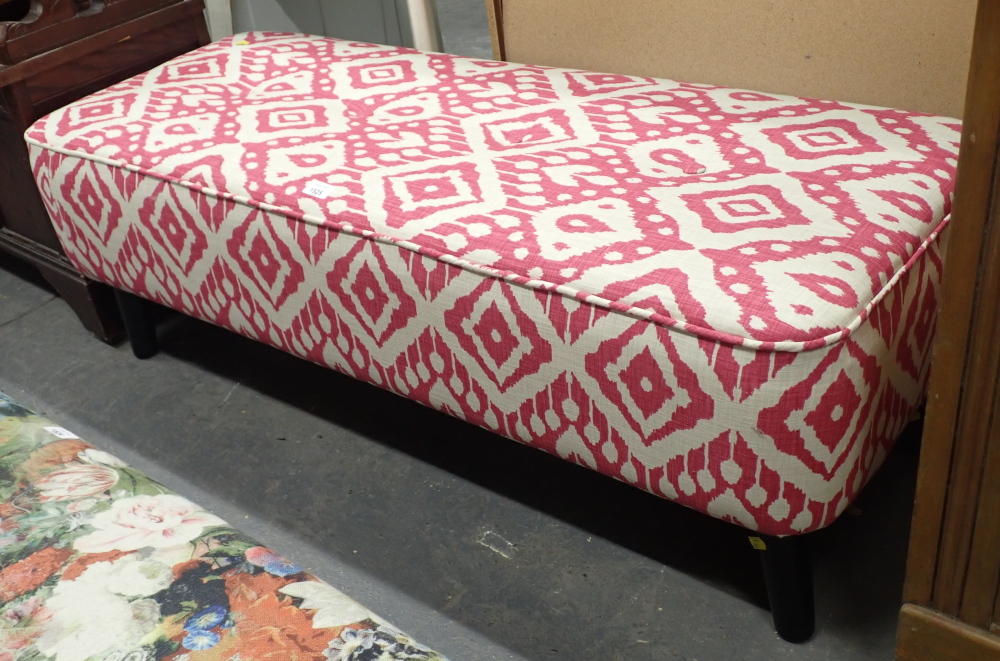 A modern finish long stool, decorated on pink and cream ground, with ebonised legs.