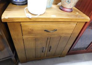 An pine short sideboard, above arrangement of single drawer and two cupboard doors.