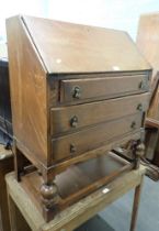 A 1950s oak bureau, the fall flap opening to reveal a fitted interior above three drawers, on bulbou