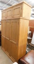 A pine triple wardrobe, with three cupboard doors above three door top box.