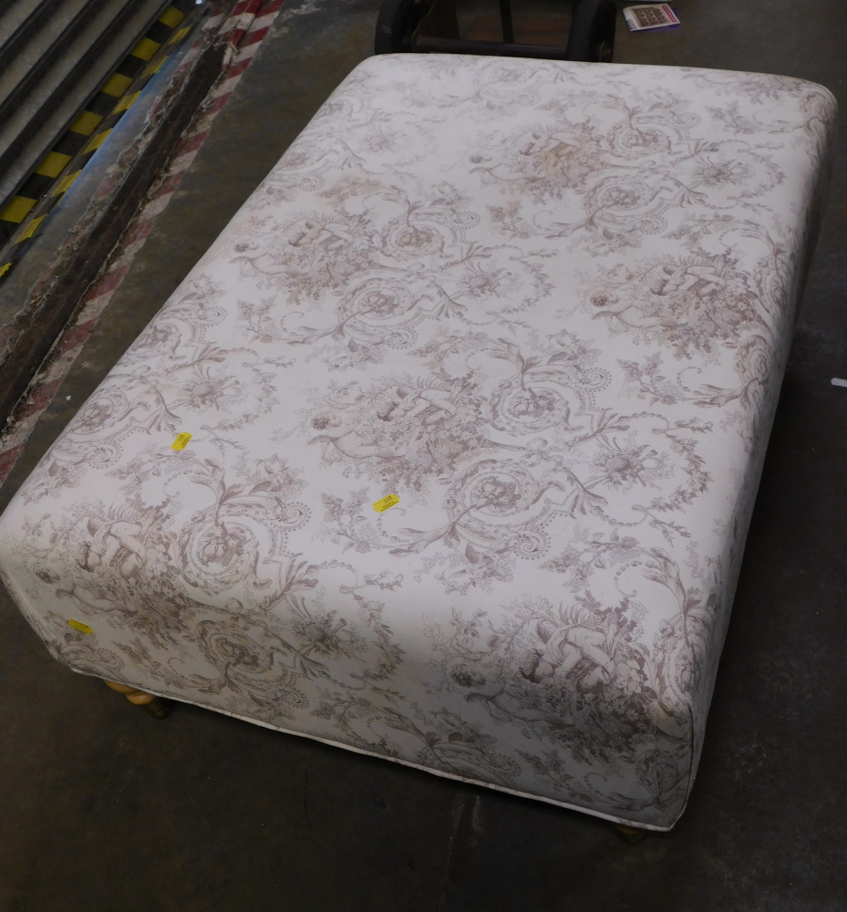 A rectangular material studded footstool, decorated with cherubs, on beech legs.