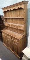 A rustic pine dresser, arched plate rack top above arrangement of four drawers, on sideboard base wi