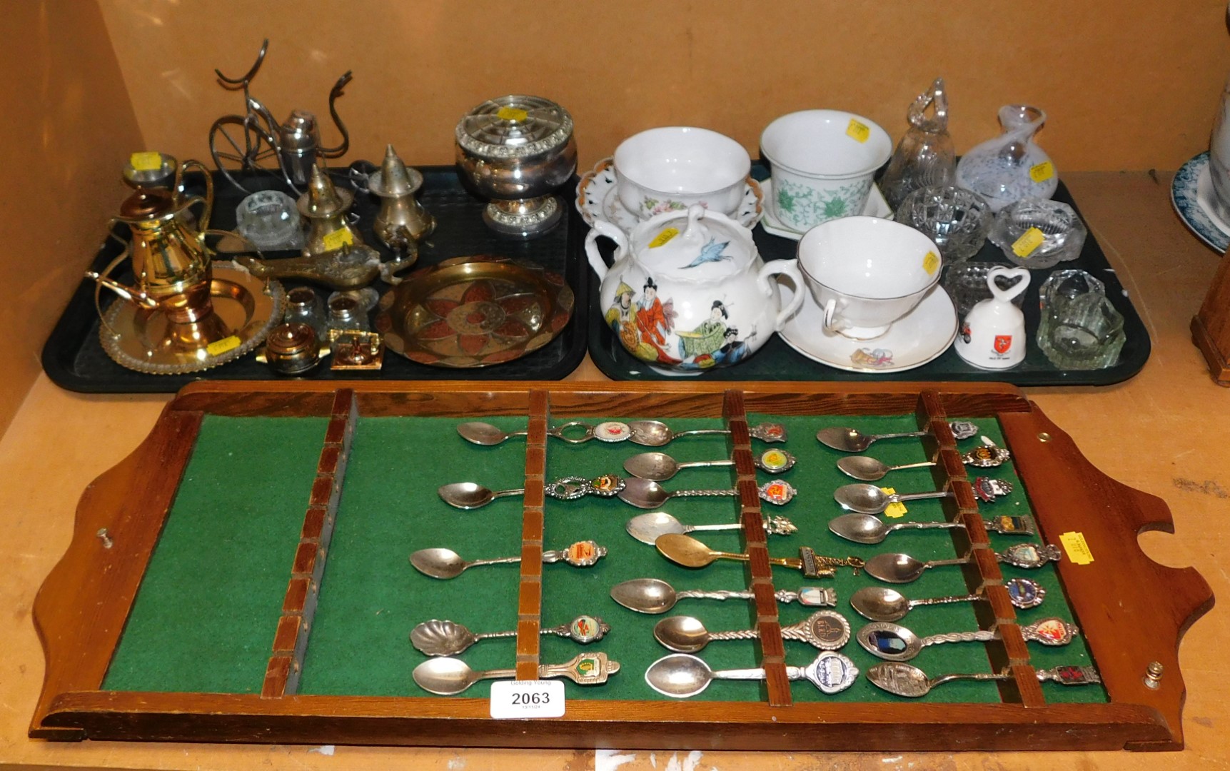 A collection of souvenir spoons, from around the world, displayed on a wall mounted panel, together