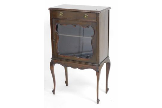 A Victorian mahogany display cabinet, with a single drawer over a shaped glazed door, enclosing a si