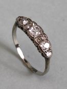 Unmarked white Gold Diamond ring set with nine diamonds, the largest central diamond flanked by a