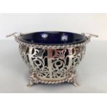 Silver hallmarked open work or pierced design basket with twin handles on four splayed feet