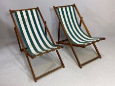 Pair of vintage wooden framed deckchairs with green and white striped fabric