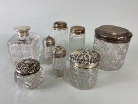 Collection of eight glass and hallmarked silver lidded jars and bottles