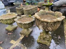 Three similar concrete garden planters on plinths