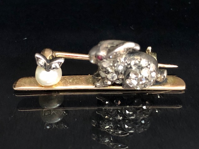 Yellow metal bar brooch mounted with a white metal diamond set rabbit staring at a pearl apple