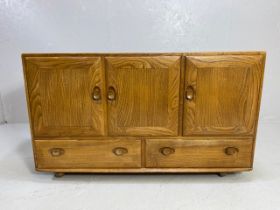 Ercol sideboard with three cupboards and two drawers under, in blond teak and on castors, approx