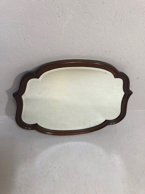 Antique mirror of bevel edged glass set in a polished mahogany scroll frame 19th century,