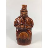 20th century treacle salt glaze bottle in the shape of a man sat on a barrel approximately 23cm