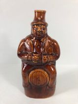 20th century treacle salt glaze bottle in the shape of a man sat on a barrel approximately 23cm