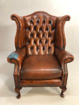 Antique style wing back chair of of good proportions upholstered caramel leather with stud