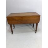 Pembroke table in flame mahogany on turned legs on casters, drawers to either end