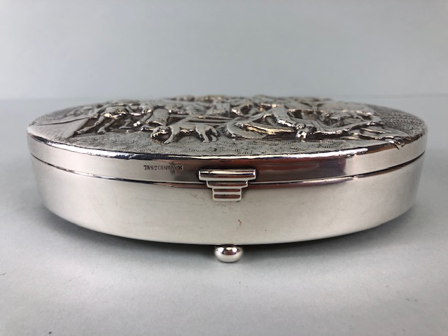 Danish white metal toilet or trinket box, oval shape on bun feet the lid embossed with a drunken - Image 2 of 7