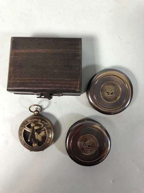Three brass pocket compasses one in a wooden box