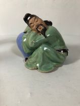 Chinese style figure of a man asleep on a vase approximately 12cm high