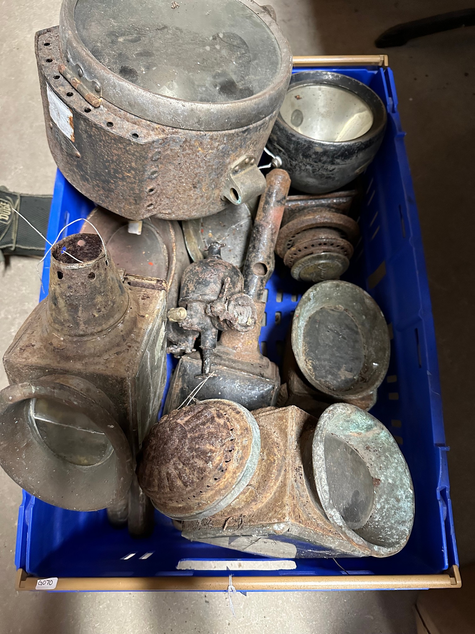 A box containing various carriage lamps and a Ford Model T carburettor.