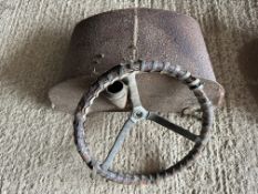 A vintage car steering wheel and fuel tank.