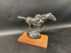 A car accessory mascot in the form of a horse and jockey on wooden display base.