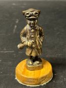 A circa 1920 Motorist car accessory mascot holding a car horn.